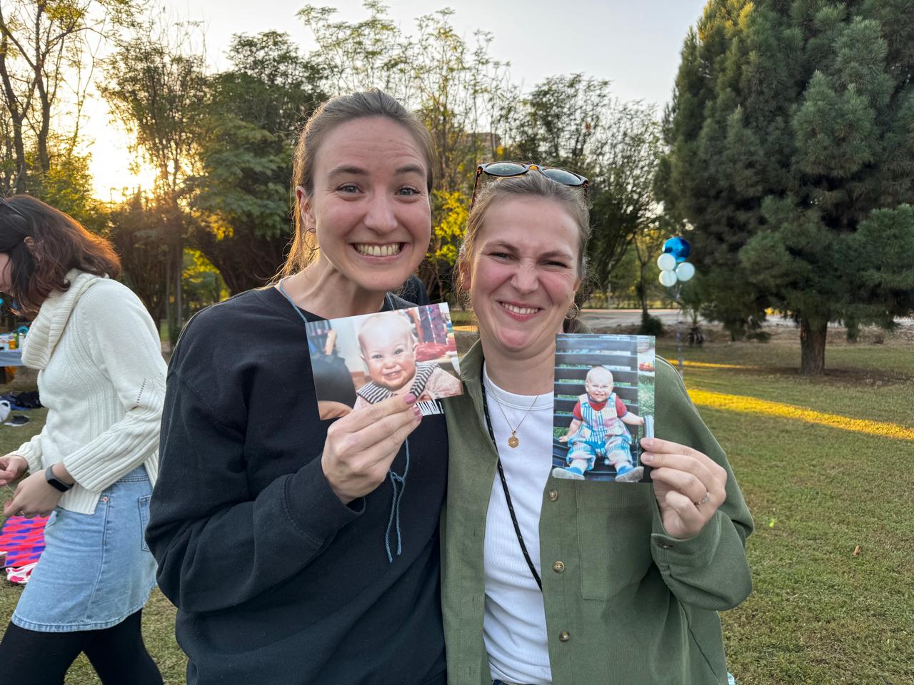 Two friends holding baby photos