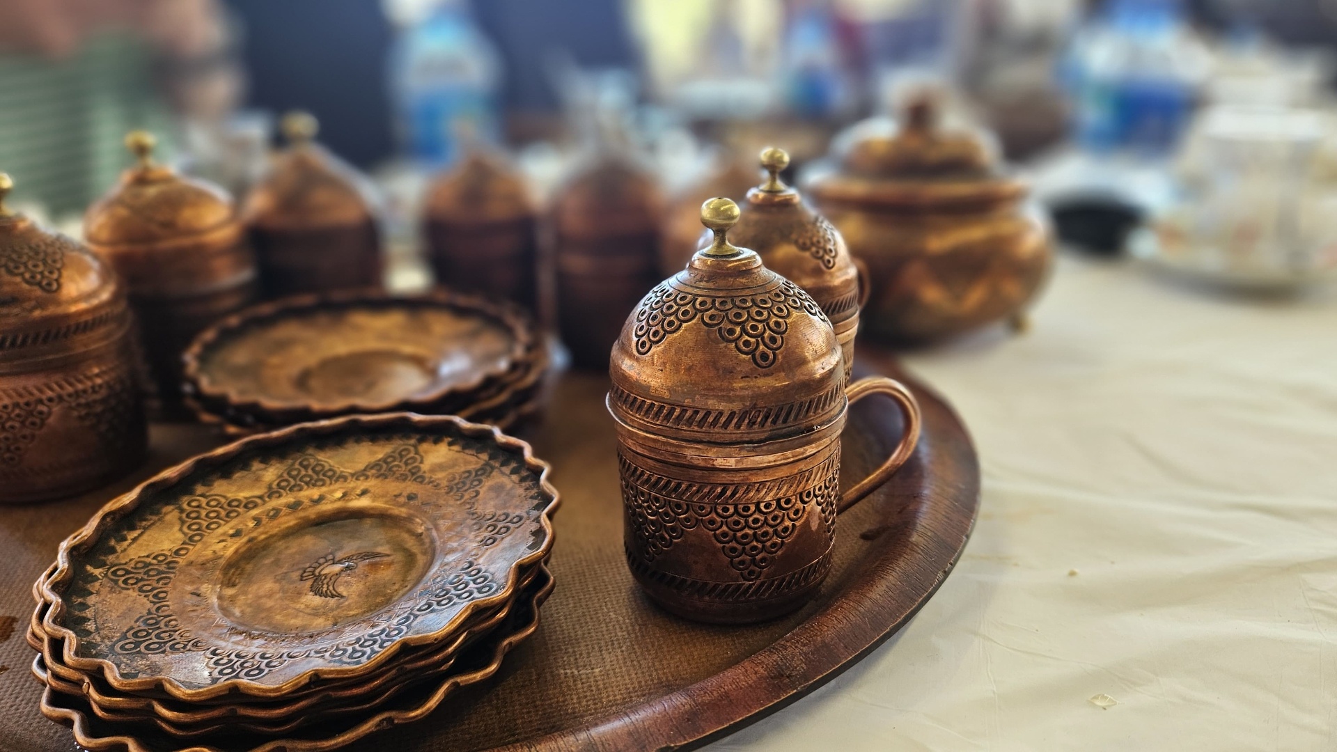 Ornate copper chai cups and saucers on a wooden tray